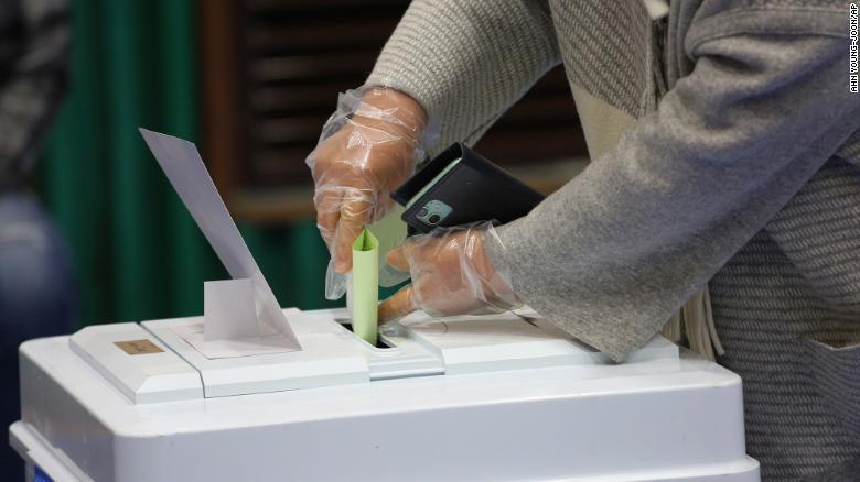 A voter wearing plastic gloves to help protect against the spread of coronavirus casts a vote for the parliamentary election at a polling station in Seoul.